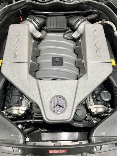 Mercedes log book open on a workbench beside fresh oil, filters and service tools.
