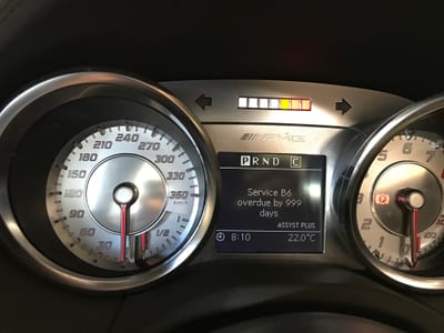 Diagnostic scan tool plugged into a Mercedes AMG showing fault codes on a laptop screen.